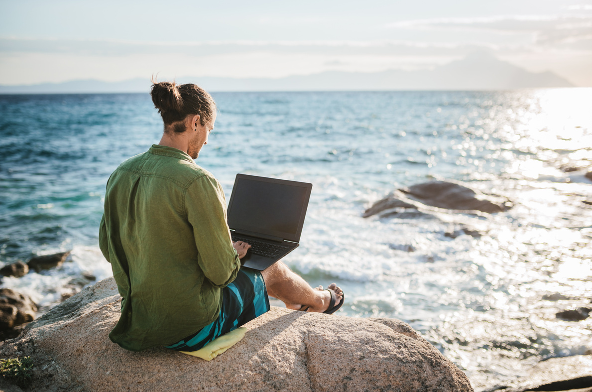 Young digital nomad man working by the sea